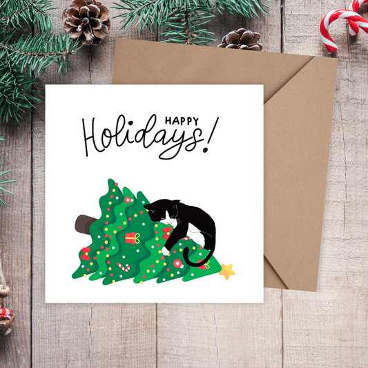 Holiday card with a cat on a Christmas tree and 'Happy Holidays!' text, surrounded by festive decorations on a wooden surface.3D Cat on the Tree Christmas Card