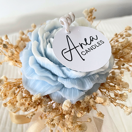 Light blue flower-shaped candle with 'Area Candles' tag on a bed of dried flowers.SANDALWOOD BLUE FLOWER CANDLE BOUQUET