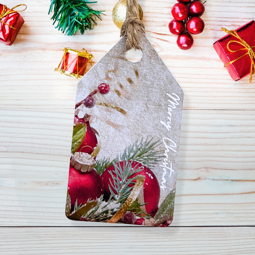 Decorative Christmas tag with red ornaments and pine branches on a wooden surface.Bauble Christmas Gift Tag Set