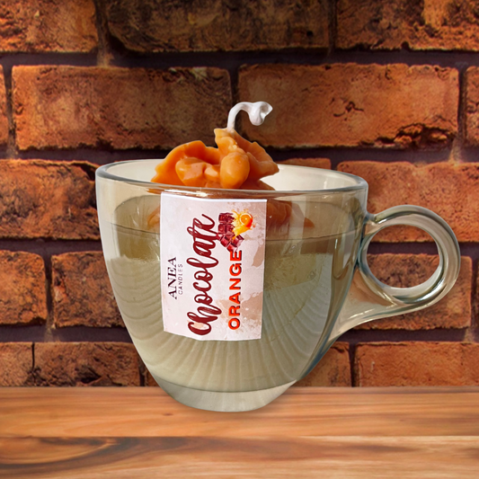 Clear mug with 'Chocolate Orange' candle labeled against a brick wall background. CHOCOLATE ORANGE PLANT CANDLE