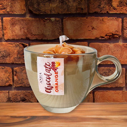 Clear mug with a chocolate orange flavor tag against a brick wall background. CHOCOLATE ORANGE FLOWERS CANDLE