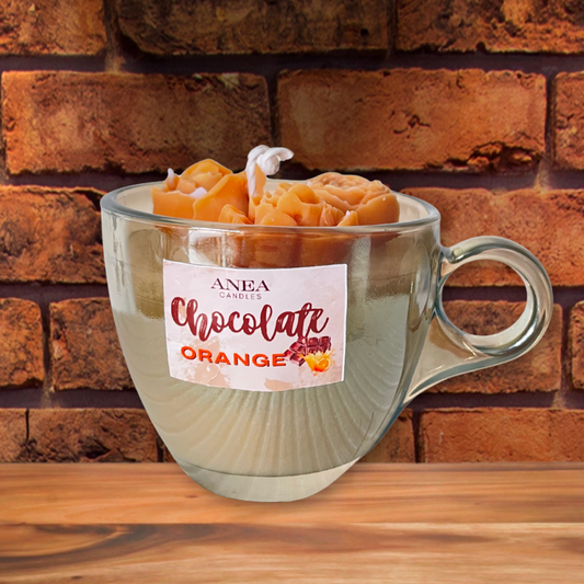 Glass mug with a candle labeled 'Chocolate Orange' against a brick wall background. CHOCOLATE ORANGE ROSES CANDLE
