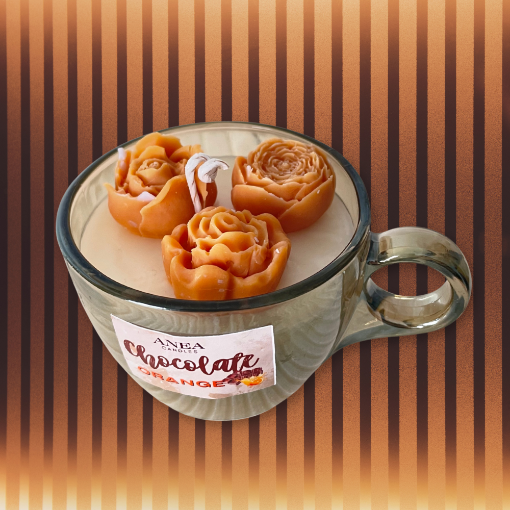 Candle shaped like a cup of chocolate orange with decorative elements on a striped background. CHOCOLATE ORANGE ROSES CANDLE