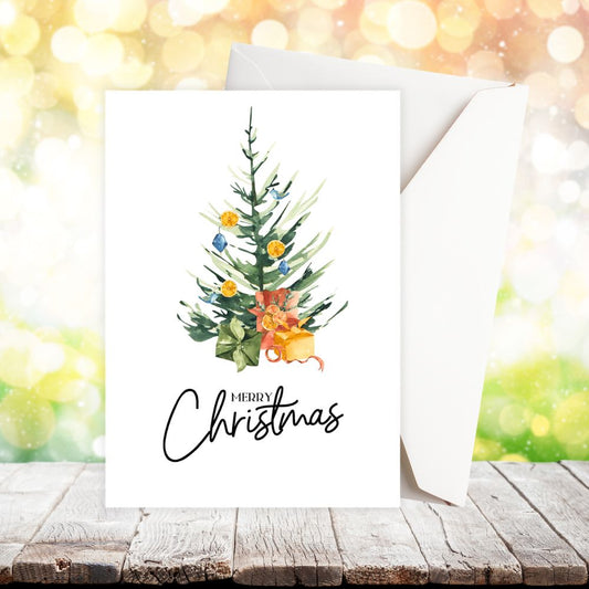 Greeting card with Christmas tree design and 'Merry Christmas' text on a wooden surface with blurred lights in the background. CHRISTMAS TREE CARD