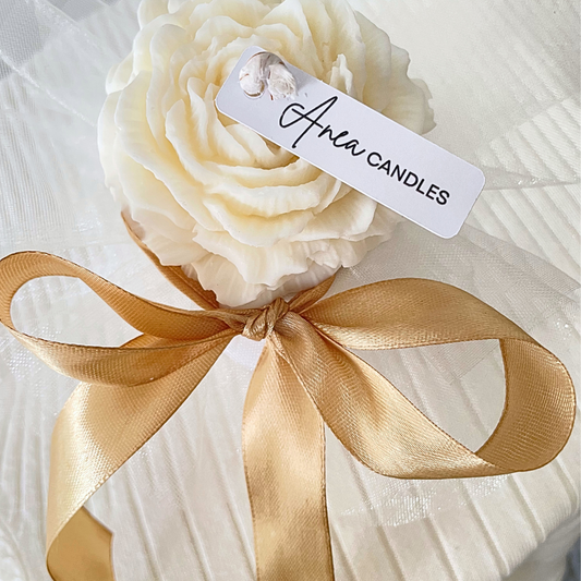White rose-shaped candle with a gold ribbon and 'Aria Candles' tag on a white background. SNOW PIXIE GOLD FLOWERS CANDLE BOUQUET