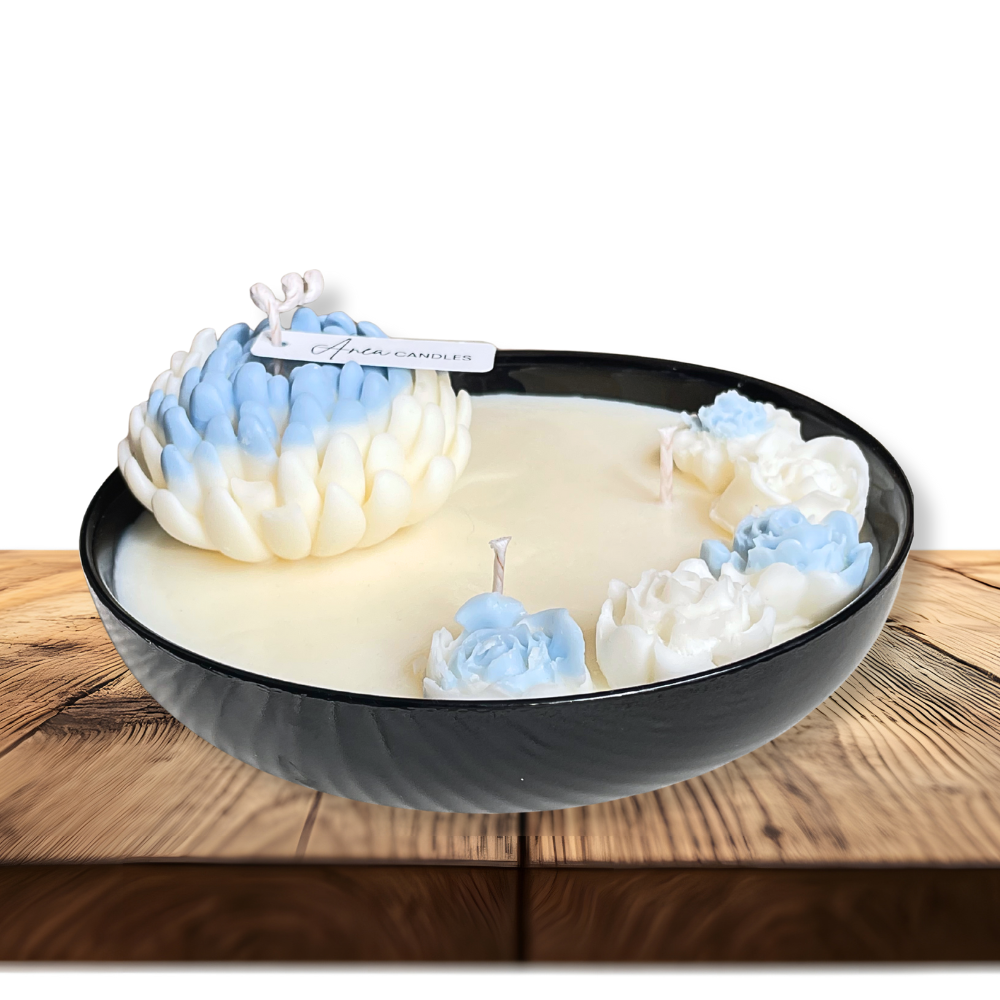 Decorative candle with floral designs in a black bowl on a wooden surface. FLOWER NATURAL SOY CANDLE