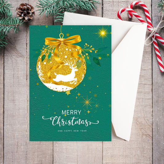 Christmas card with gold ornament and reindeer design on a green background, placed on a wooden surface with festive decorations. Golden Bauble with Reindeer Christmas Card