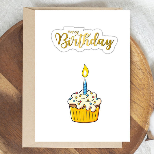 Birthday card with a cupcake illustration and 'Happy Birthday' text on a wooden surface. Golden Cupcake Happy Birthday Card