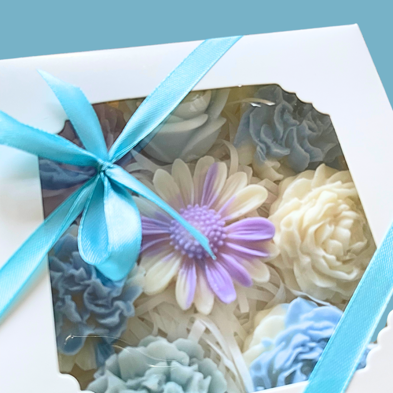 Decorative soap flowers in a box with a blue ribbon on a light blue background. PASTEL FLOWERS WAX MELTS GIFT BOX