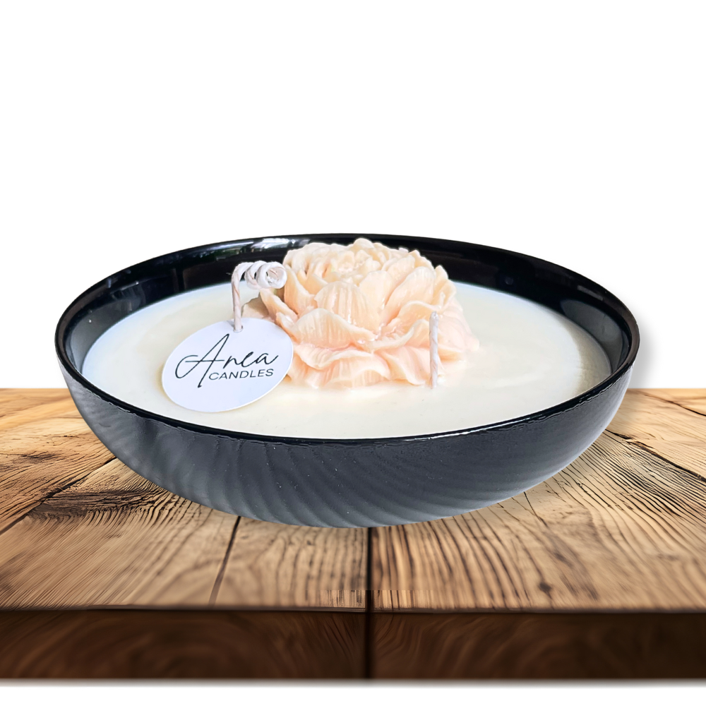 Decorative candle in a black bowl with a floral design on a wooden surface. PEONY FLOWER SOY NTURAL CANDLE