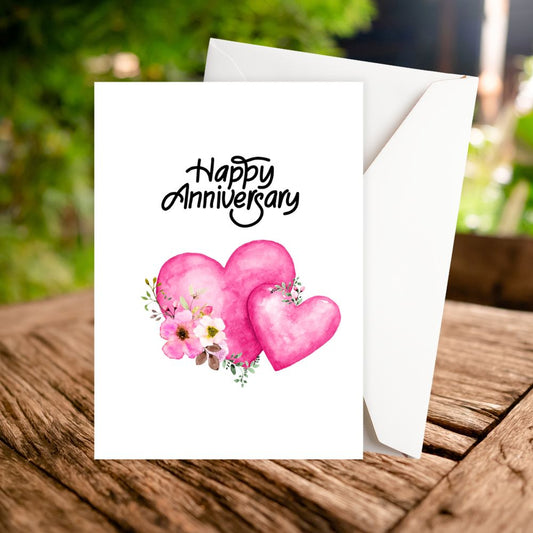 Greeting card with 'Happy Anniversary' text and pink hearts on a wooden surface.PINK HEARTS ANNIVERSARY CARD