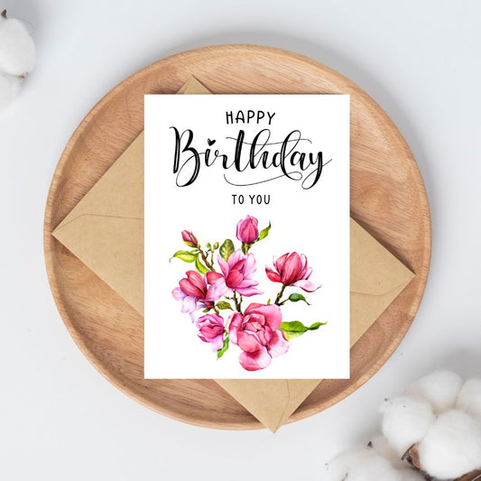 Birthday card with floral design and 'Happy Birthday to You' text on a wooden plate. Pink Magnolia Happy Birthday Card