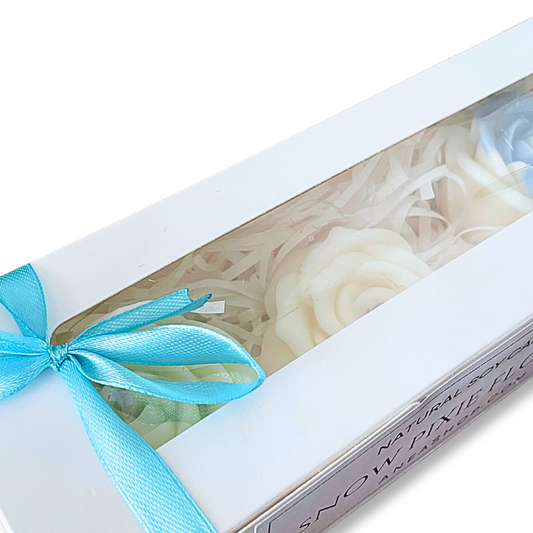 Gift box with white flowers and a blue ribbon on a white background. ROSES SNOW PIXIE CANDLE