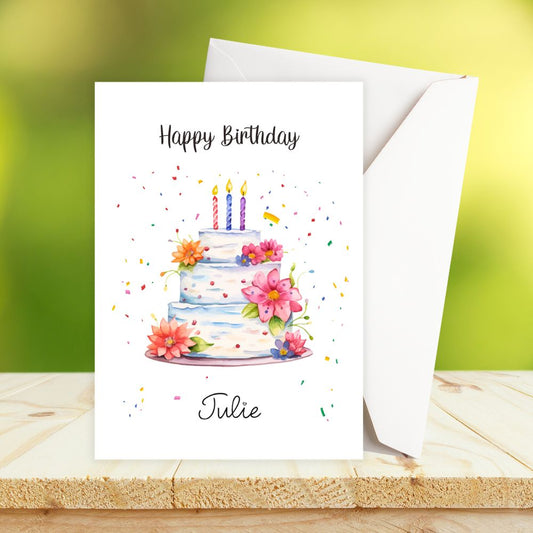 Personalised Birthday card with a cake illustration and 'Happy Birthday Julie' text on a wooden surface.