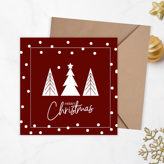 Red Christmas card with white trees and 'Merry Christmas' text, accompanied by a brown envelope on a light gray background. Trees Burgundy Christmas Card