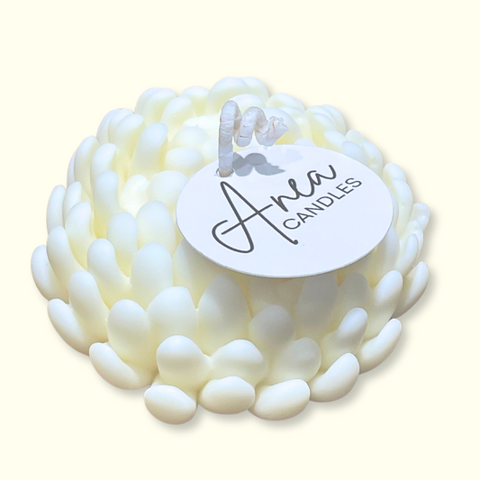 White candle with a decorative top and 'Anea Candles' label on a white background. PEONY SNOW PIXIE SOY CANDLE