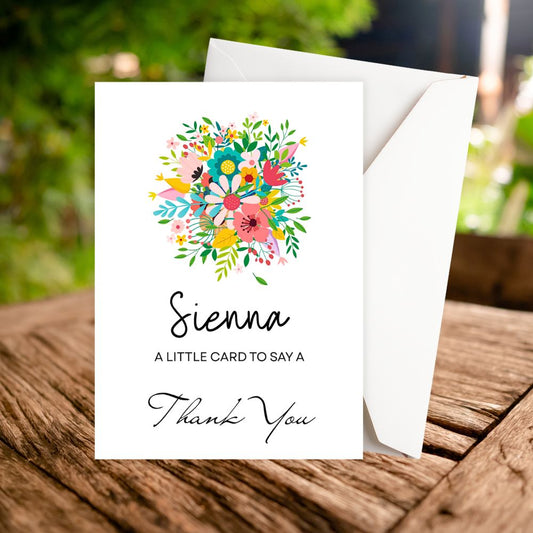 Greeting card with floral design and 'Sienna' branding on a wooden surface. Wild Flower Bouquet Thank You Personalised Card