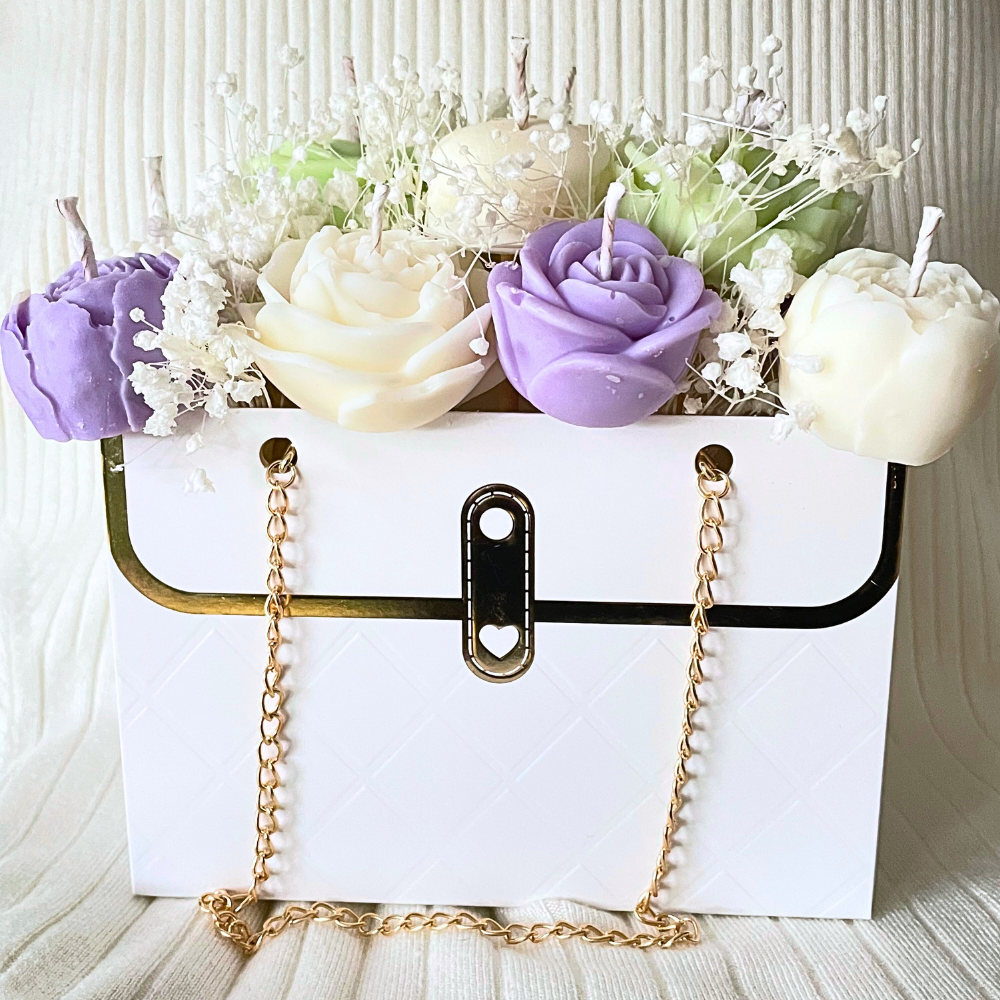 White handbag with gold chain and decorative candles shaped like flowers on a white background. LILAC & GREEN CANDLE FLOWER BOUQUET BAG