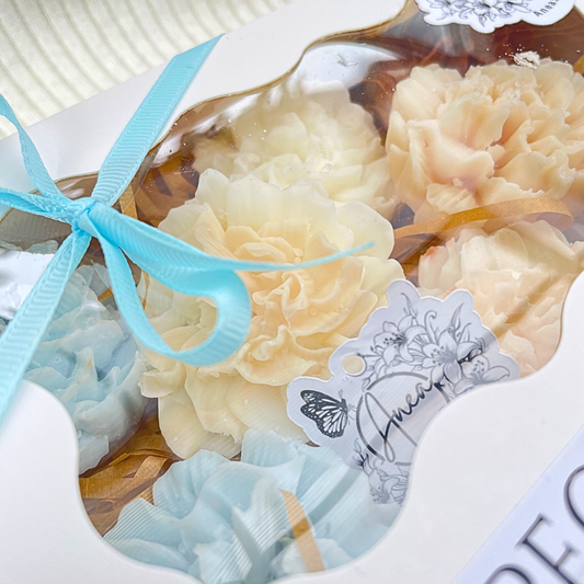 Decorative soap flowers with a blue ribbon and a tag on a white surface. flowers WAX MELTS GIFT BOX