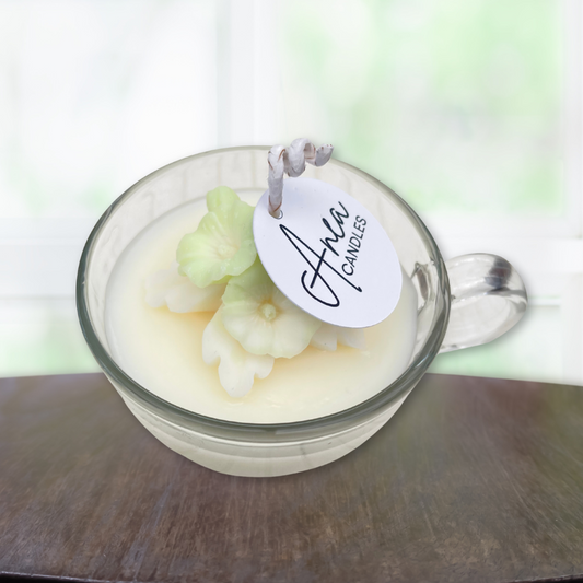 Glass candle with floral design and 'Aiva Candles' tag on a wooden surface. sandalwood candy floss candle