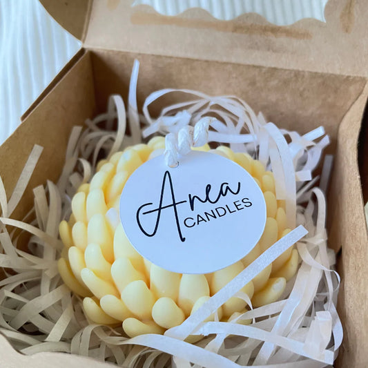 Yellow candle in a box with 'Anea Candles' label. SANDALWOOD YELLOW FLOWER CANDLE