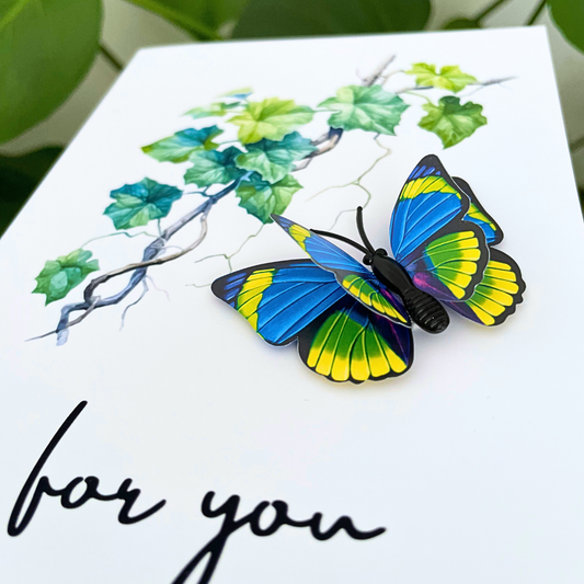 Colorful butterfly-shaped hair ties on a card with 'for you' text and green leaves. 3D Blue Butterfly For You Greeting Card