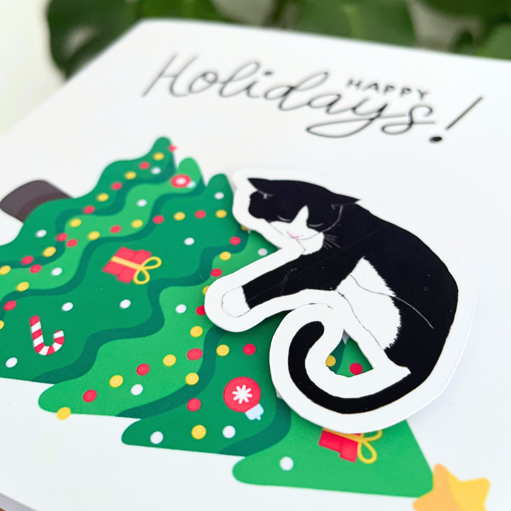 Holiday card with a black and white cat climbing a decorated Christmas tree, featuring the text 'Happy Holidays!'.3D Cat on the Tree Christmas Card