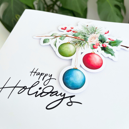 Decorative card with Christmas ornaments and 'Happy Holidays' text on a white background. 3D Holidays Bauble Christmas Card