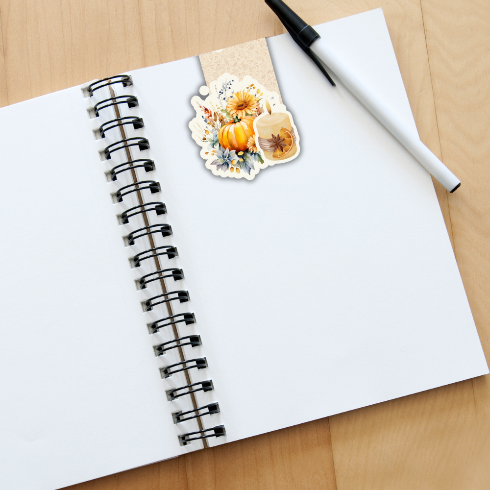 Open notebook with a pen and decorative sticker on a wooden surface. AUTUMN PUMPKIN AND CANDLE MAGNETIC BOOKMARK