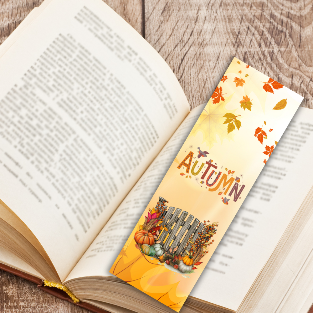 Open book with an autumn-themed bookmark on a wooden surface