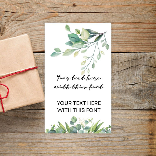 Card with green leaf design and text placeholder on a wooden surface with a gift box.BOTANICAL PERSONALISED GIFT TAG
