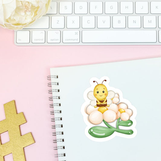 Sticker of a bee on a flower on a notebook with a keyboard in the background. Bee Relaxing on Flower Sticker