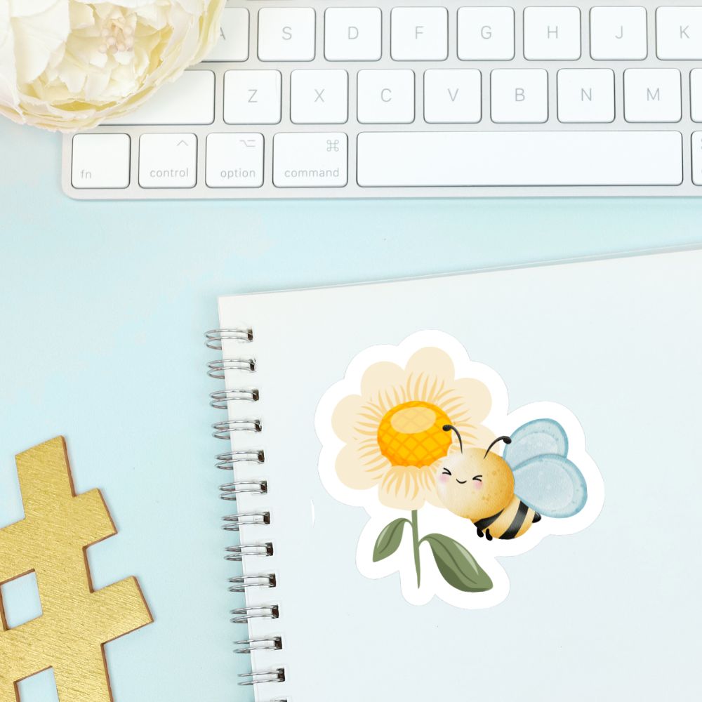 Sticker of a bee on a flower with a notebook and keyboard in the background. Bee and a Flower Sticker