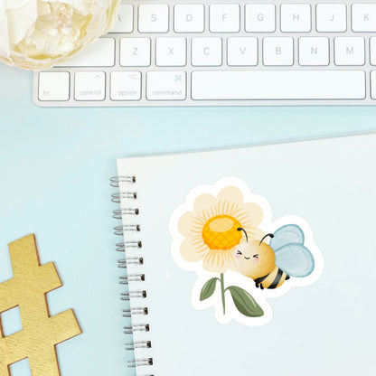 Sticker of a bee on a flower with a notebook and keyboard in the background. Bee and a Flower Sticker