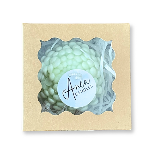 Green candle in a decorative box with 'Anea Candles' label. PEONY SNOW PIXIE SOY CANDLE