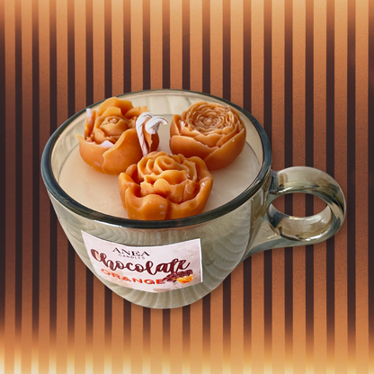 Candle shaped like a cup of chocolate orange with decorative elements on a striped background. CHOCOLATE ORANGE ROSES CANDLE