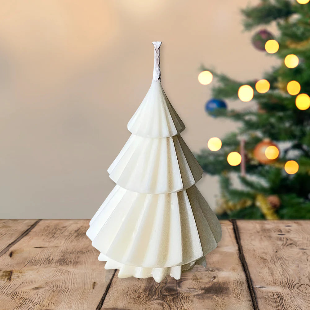 White and green paper Christmas tree on a wooden table with a blurred Christmas tree in the background. CHRISTMAS TREES CANDLE GIFT BOX