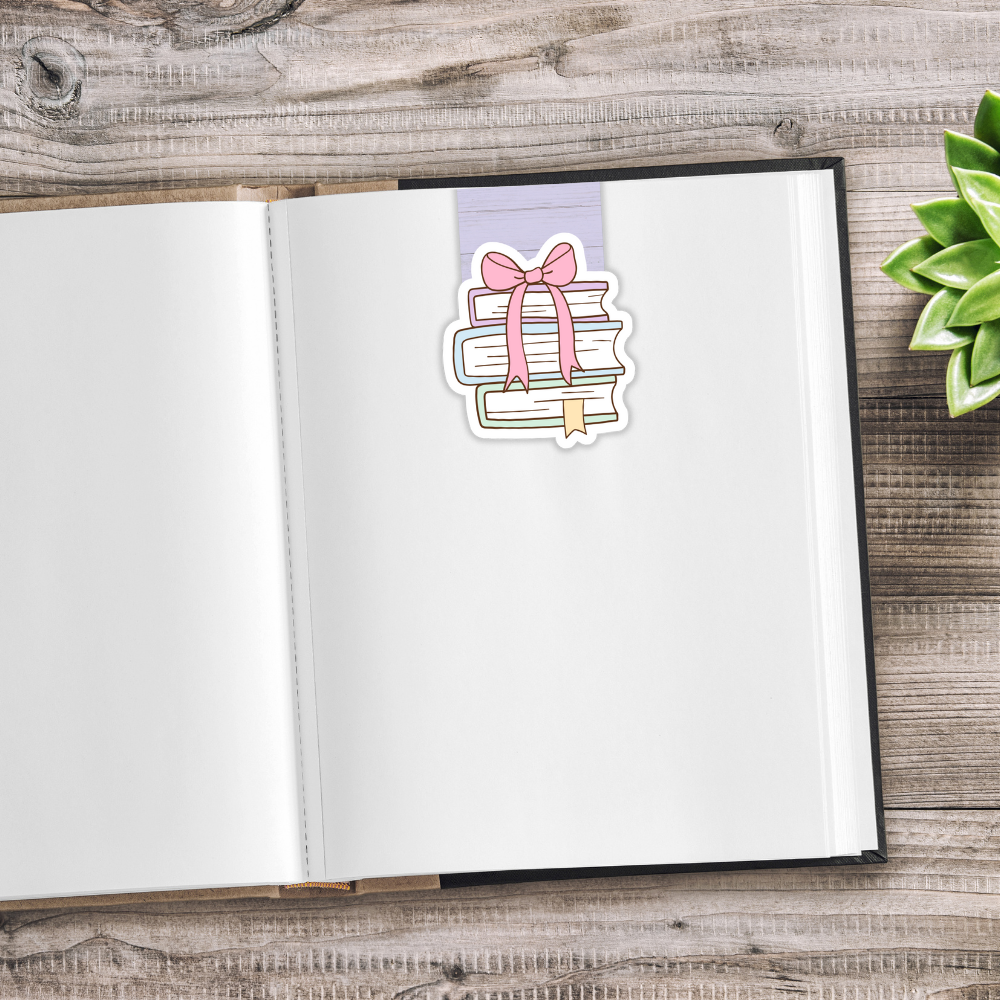 Open notebook with a decorative sticker of books and a bow on a wooden surface.CUTE BOOKS MAGNETIC BOOKMARK SET