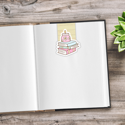 Open notebook with a sticker of books and a candle on a wooden surface. CUTE BOOKS MAGNETIC BOOKMARK SET