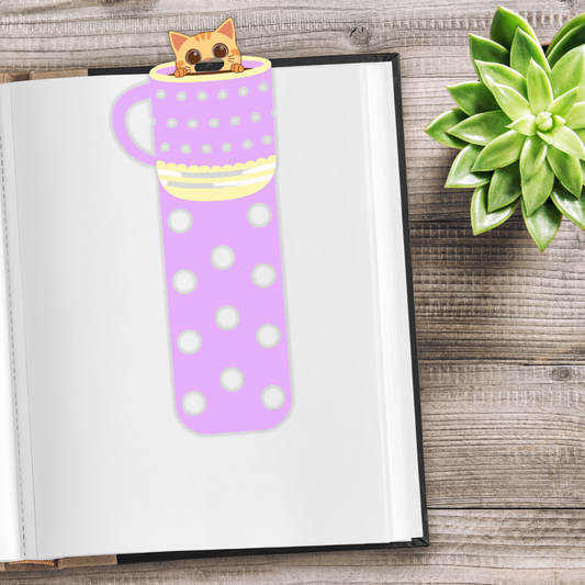 Purple polka dot mug-shaped bookmark on a book with a succulent plant on a wooden surface. Cat in the mug Bookmark