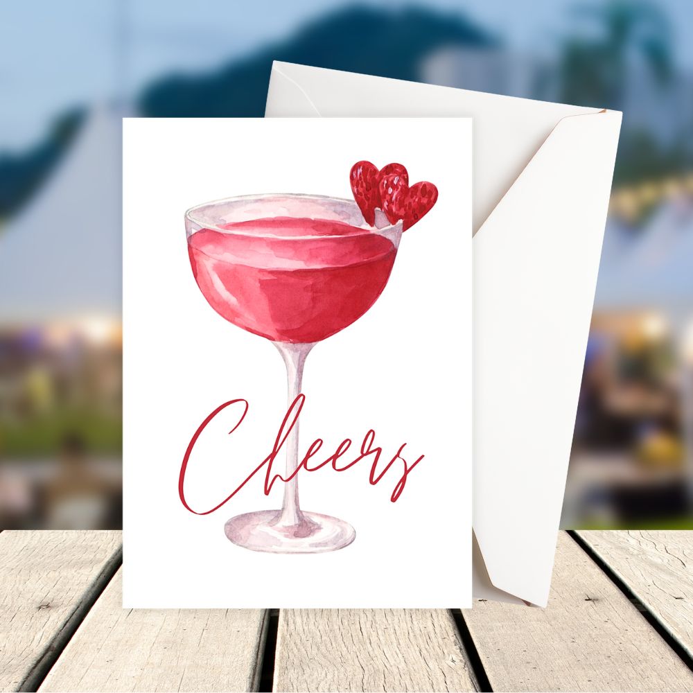 Greeting card with a pink cocktail and 'Cheers' text on a blurred outdoor background. Cheers wine Hearts Birthday Card 