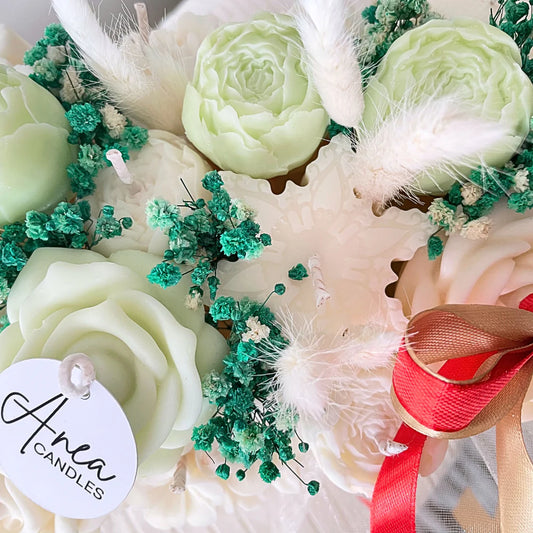Decorative flower arrangement with green and white flowers, a red ribbon, and a 'Area Candles' tag.Christmas natural soy candle