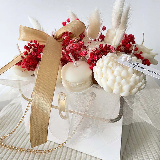 Decorative arrangement with candles, red flowers, and a gold ribbon on a white background. Christmas natural soy candle