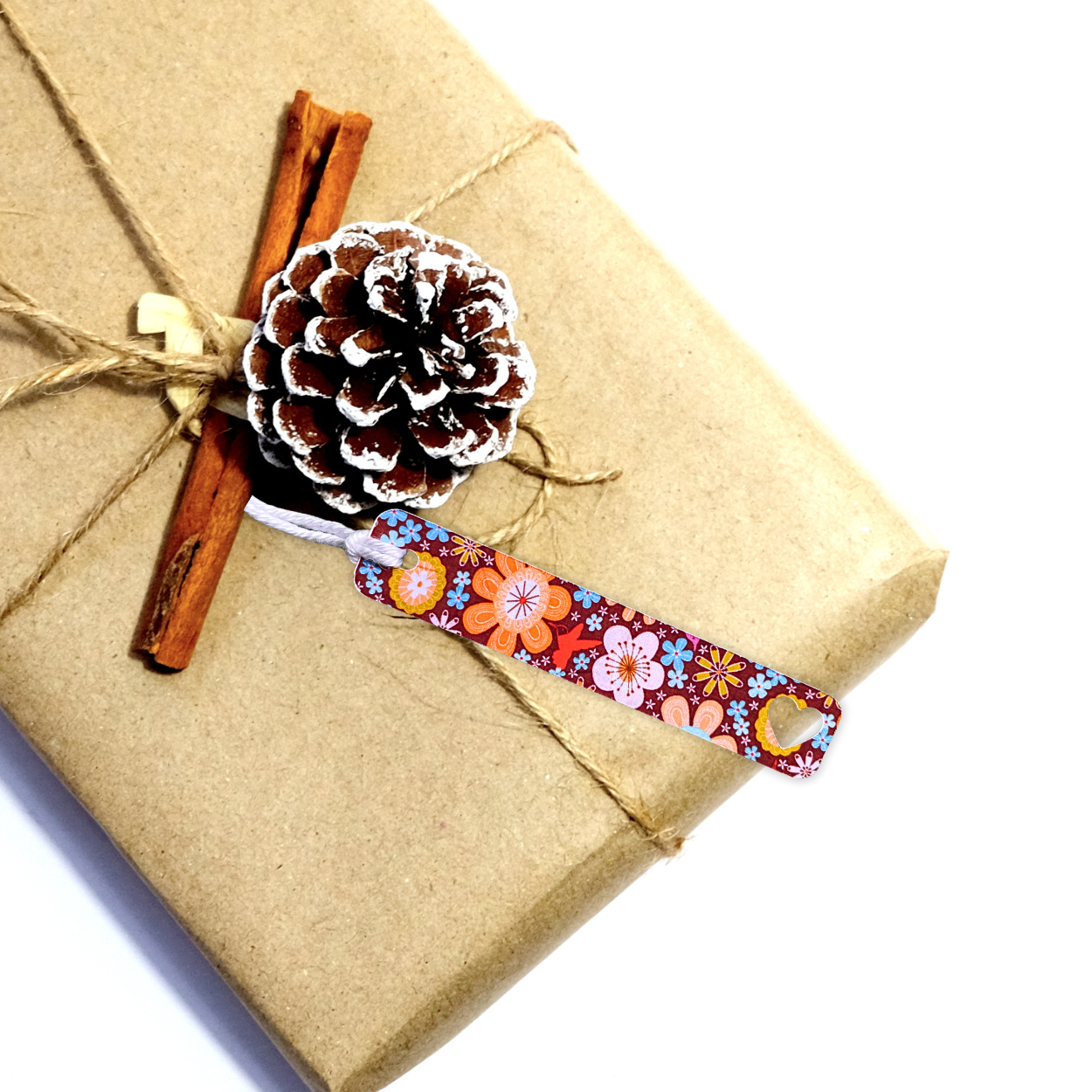 Gift wrapped in brown paper with a decorative ribbon, pine cone, and cinnamon stick on a white background. FLORAL SLIM GIFT TAG SET 1