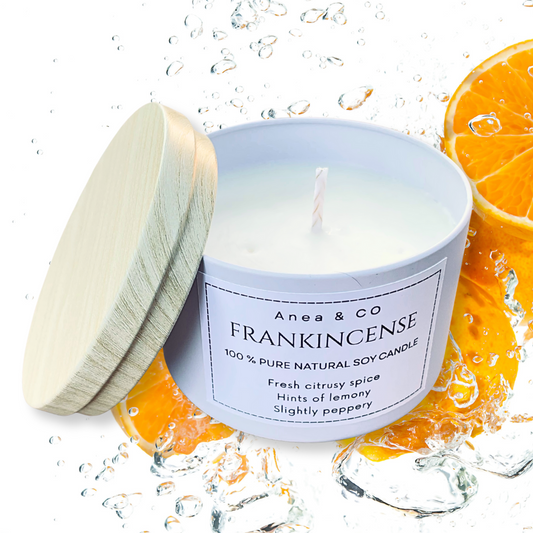 Candle with a wooden lid on a white background, surrounded by orange slices.FRANKINCENSE NATURAL SOY CANDLE