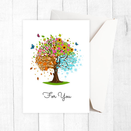 Colorful tree design with flowers and leaves on a white card, placed on a white wooden surface.