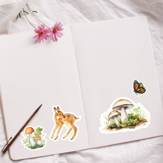 Set of nature-themed stickers including a deer, mushrooms, and a butterfly on a white surface with flowers and a pen.Forest Animals Sticker mushroom