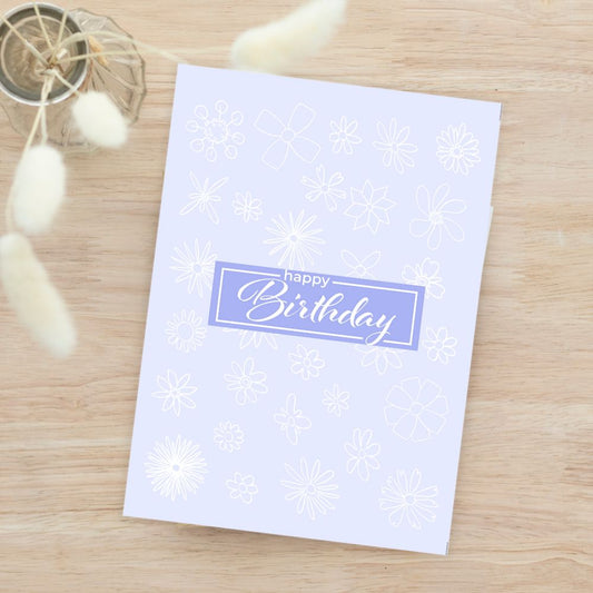 White birthday card with snowflake pattern and 'Happy Birthday' text on a wooden surface. Gentle Pastels Birthday Card