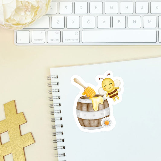 Sticker of a bee and honeycomb on a notebook with a keyboard in the background. Honey Bee Sticker