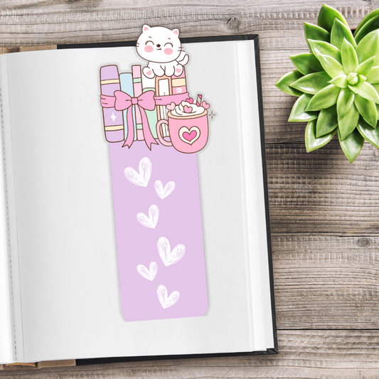 Bookmark with a cat and gift design on an open book next to a succulent plant.Kawaii Kitten Bookmark